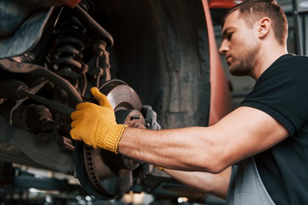 Fixing breaks man in uniform is working in the auto service