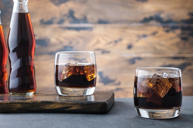 Fizzy cola with ice cubes on on wall bottle