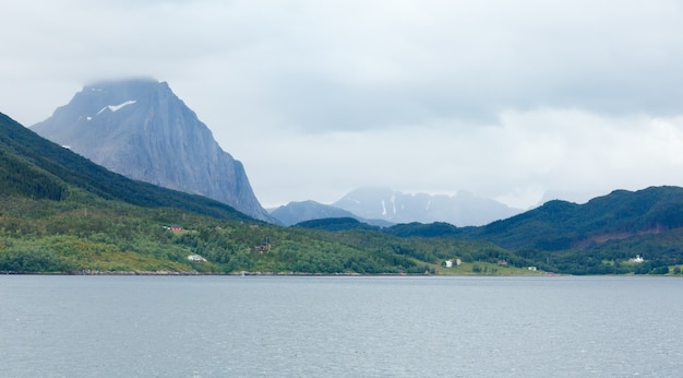 Fjord summer cloudy view with houses on coast .