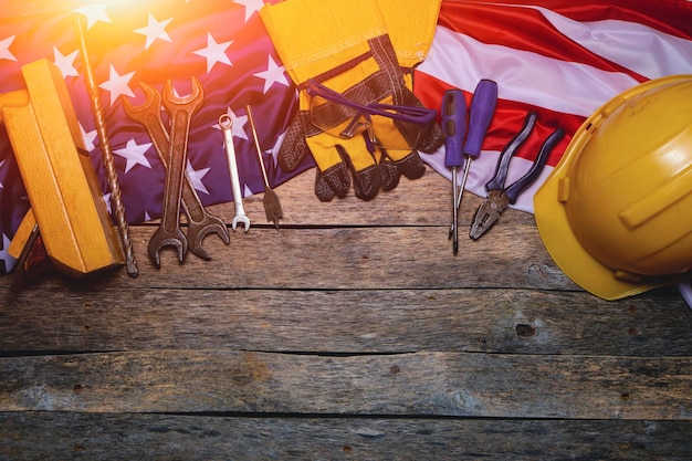 Flag America and construction tool on wooden background are illuminated by sunlightConcept Labor Day first May