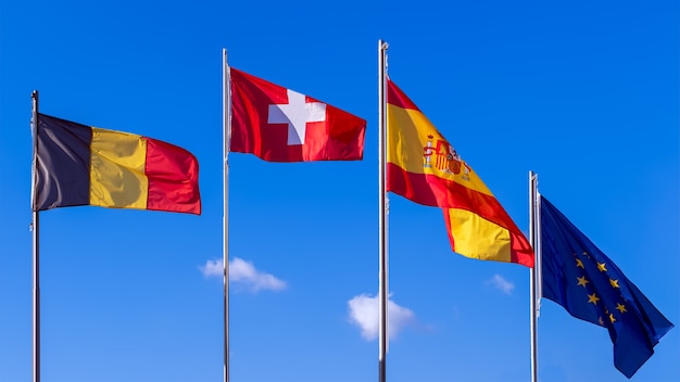 Flag of Belgium, flag of Switzerland, flags of Spain and flag of European Union on blue sky