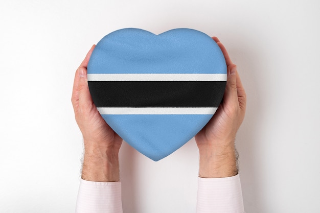 Bandiera del botswana su una scatola a forma di cuore in mani maschili.