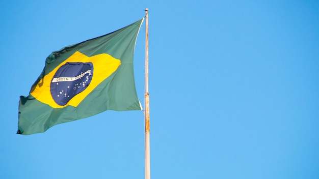 Flag of Brazil outdoors with a beautiful blue sky in the background in Rio de Janeiro Brazil.