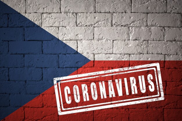 オリジナルのプロポーションを持つチェコ共和国の旗。コロナウイルスの刻印。レンガの壁のテクスチャ。コロナウイルスの概念。 COVID-19または2019-nCoVパンデミックの危機に瀕しています。