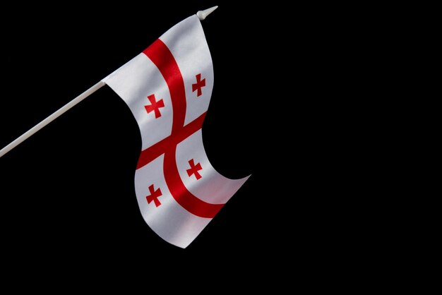 The flag of georgia on a black background develops and flies waving in the wind isolate