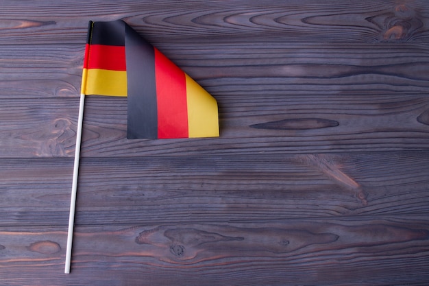 The flag of germany with stick and copy space on grey wood