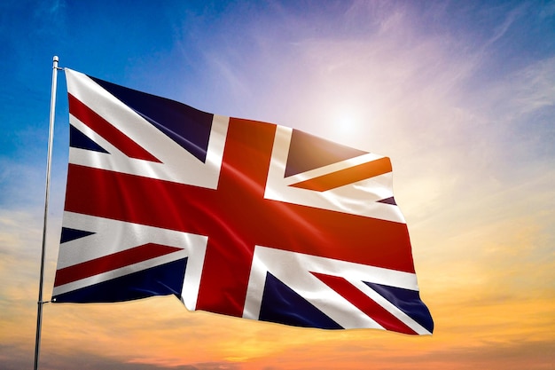 Flag of Great Britain being waved in the breeze against a sunset sky.