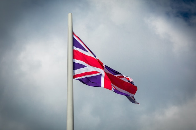 Флаг Великобритании развевается на ветру против облачного неба