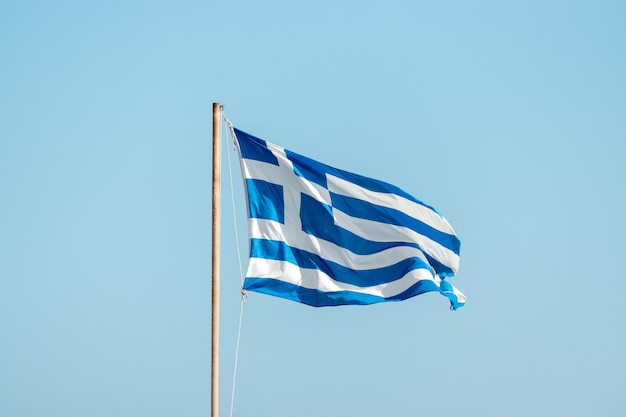 Flag of Greece on flagpole against the blue sky