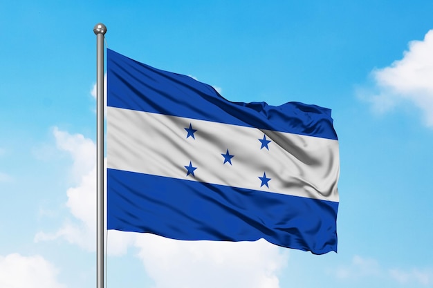 A flag of honduras with the blue and white flag on a pole against a blue sky.