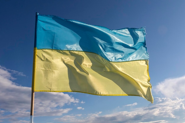 The flag of independent Ukraine is blowing in the wind against the blue sky and the setting sun