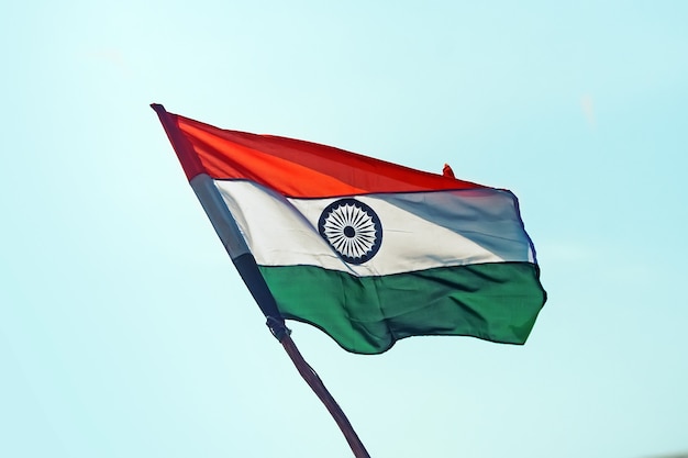 Flag of India on wind. Indian flag develops against the background of the blue cloudless sky.