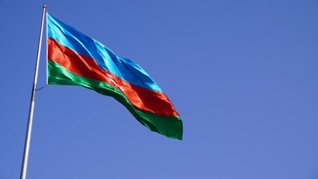 Photo a flag is flying in the wind against a blue sky