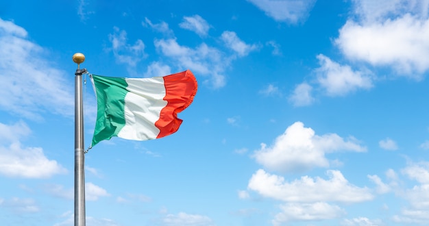 Flag of Italy over a blue sky with clouds