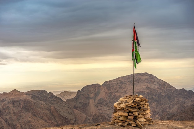 The flag of Jordan on the top of Mount Petra on a cloudy day