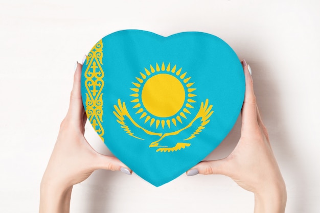 Flag of Kazakhstan on a heart shaped box in a female hands. White 