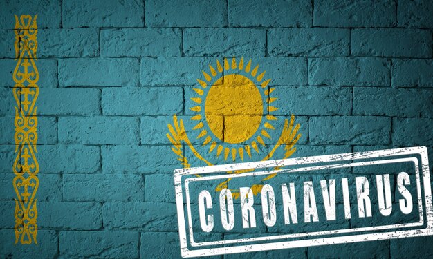 Flag of the Kazakhstan with original proportions. stamped of Coronavirus. brick wall texture. Corona virus concept. On the verge of a COVID-19 or 2019-nCoV Pandemic.