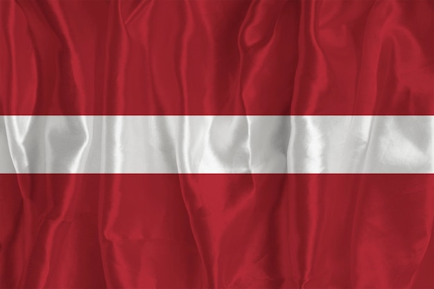 The flag of Latvia on a silk background is a great national symbol Texture of fabrics The official state symbol of the country