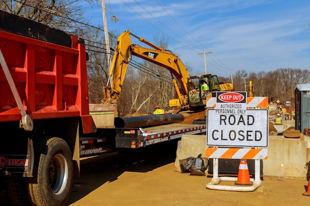 Photo flag man points to a road closed sign on a highway repair work on the road