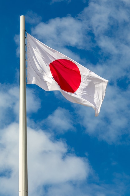 사진 일본의 국기가 구름과 하늘을 배경으로 깃대에 빨라