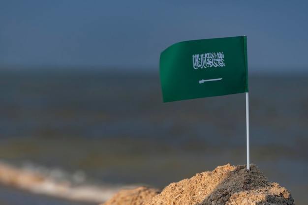 사진 바다 배경에 사우디 아라비아의 국기입니다. 사우디아라비아에서의 휴가. 칼으로 녹색 플래그입니다.