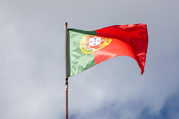 Flag of Portugal waving over cloud blue Portuguese sky