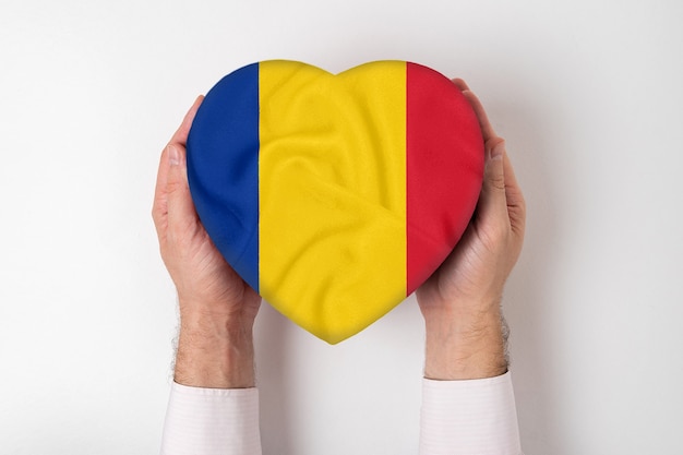 Foto bandiera della romania su una scatola a forma di cuore in mani maschili