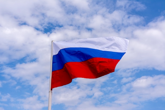 The flag of Russia flutters against the blue sky