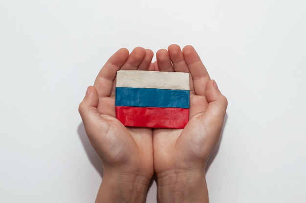 The flag of Russia made of plasticine in the hands of a child