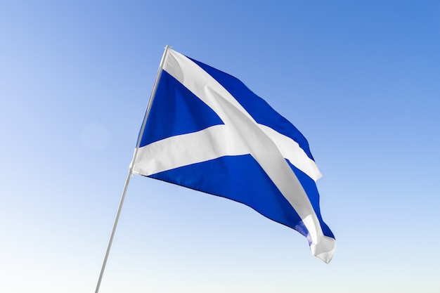 Flag of Scotland waving against clear blue sky