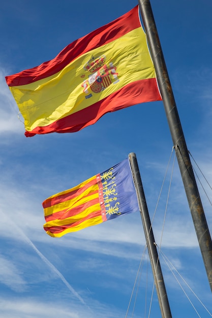 Foto bandiera della spagna e la bandiera di valencia contro il cielo blu