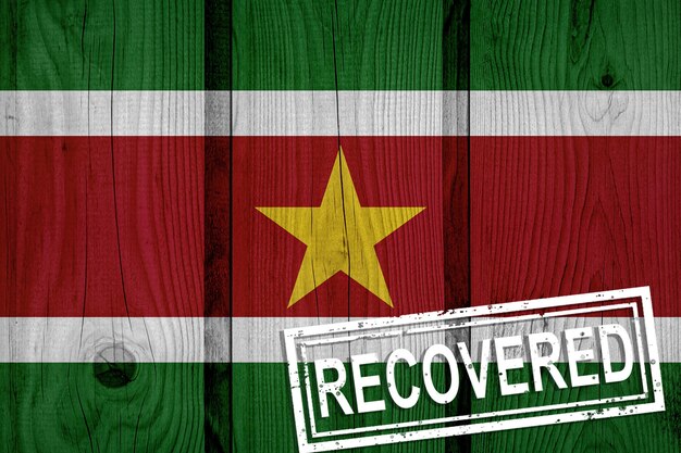 Flag of Suriname that survived or recovered from the infections of corona virus epidemic or coronavirus. Grunge flag with stamp Recovered