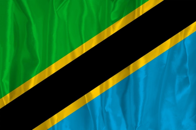 The flag of Tanzania on a silk background is a great national symbol Texture of fabrics The official state symbol of the country