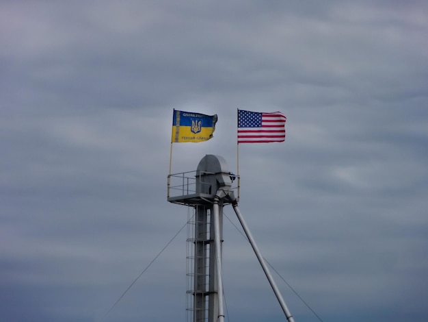 A flag on top of a metal structure with a blue and yellow flag on it.
