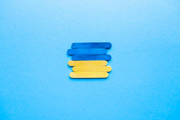 Photo flag of ukraine on a blue background top view. blue and yellow sticks. ukraine symbol