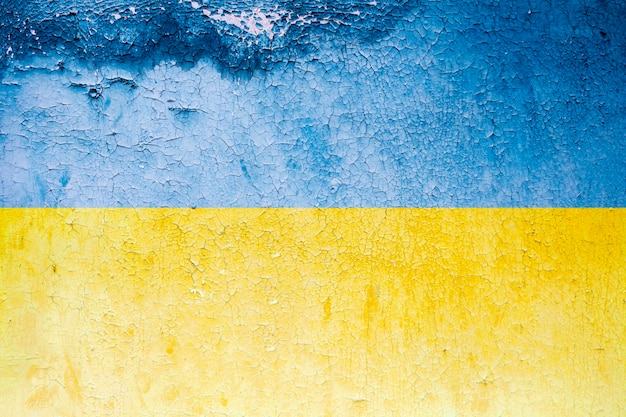 古いグランジの壁にウクライナの旗青黄色コンクリートの壁に剥がれたペンキ