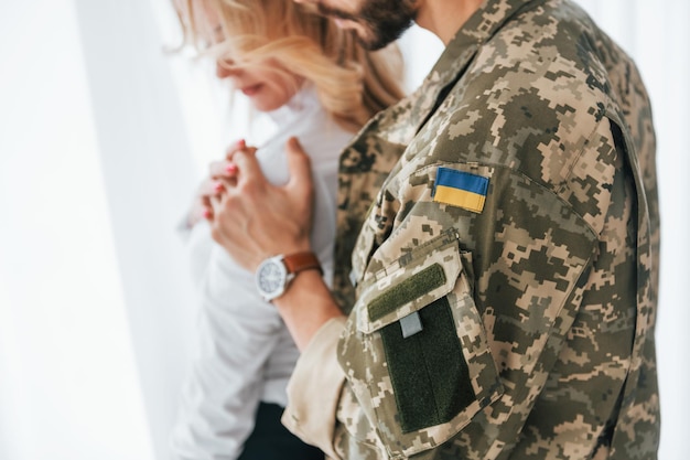 Flag of Ukraine Soldier with his wife standing indoors and embracing