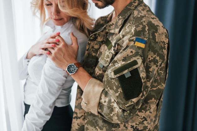 Flag of Ukraine Soldier with his wife standing indoors and embracing