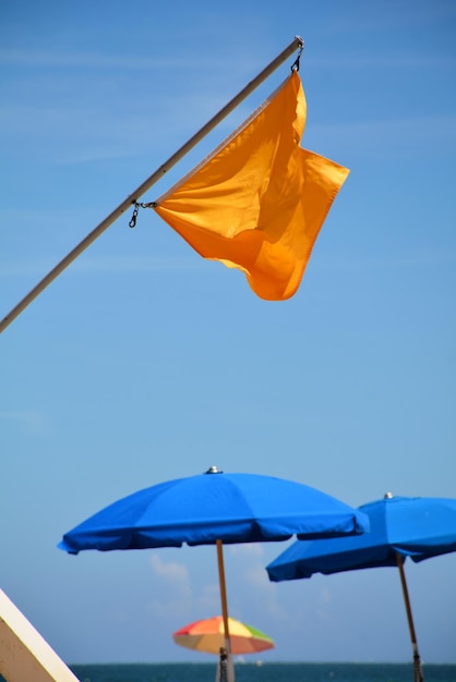 Foto bandiere e ombrelli sulla riva del mare contro il cielo blu