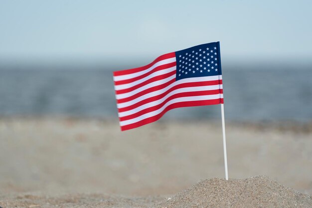 Flag of United States of America on sandy shore National flag of America sea background