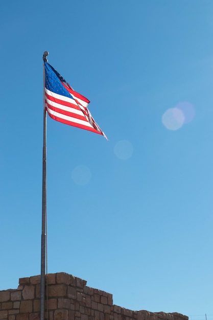 Flag of the United States waving in blue sky with flare