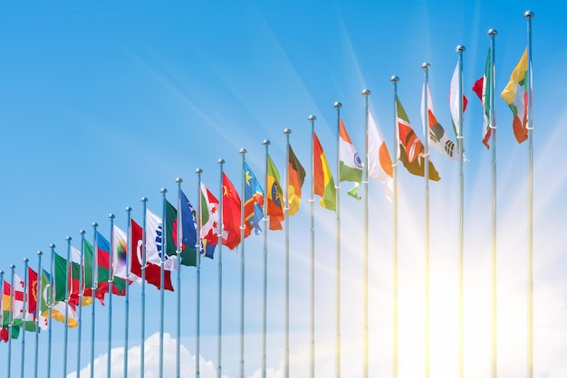 Photo flags of different countries on the background of the blue sky in the sunlight