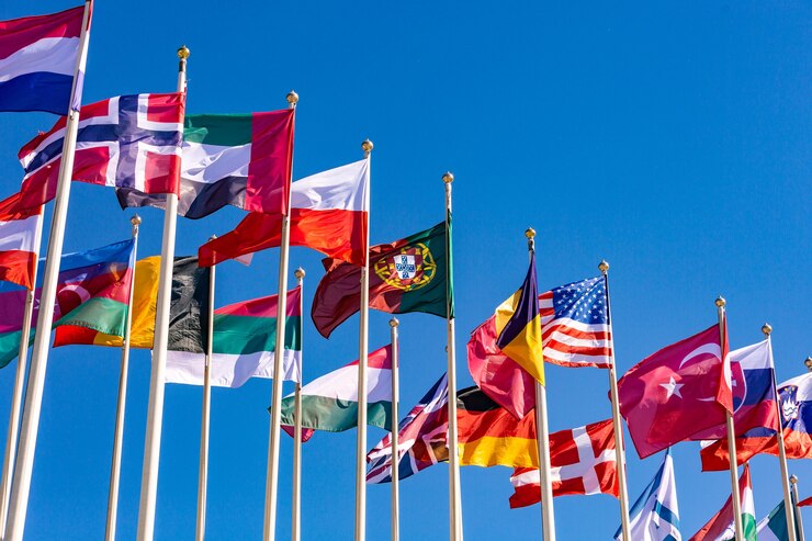 Photo flags of different countries flutters in the wind against a light blue sky