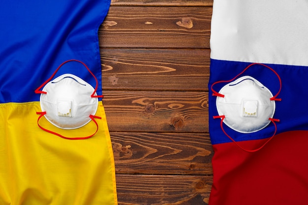 医療マスクと木製の背景にロシアとウクライナの旗