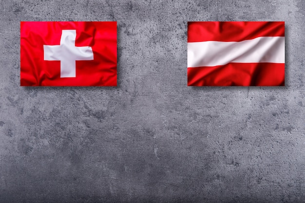 コンクリートの背景にスイスとオーストリアの旗。