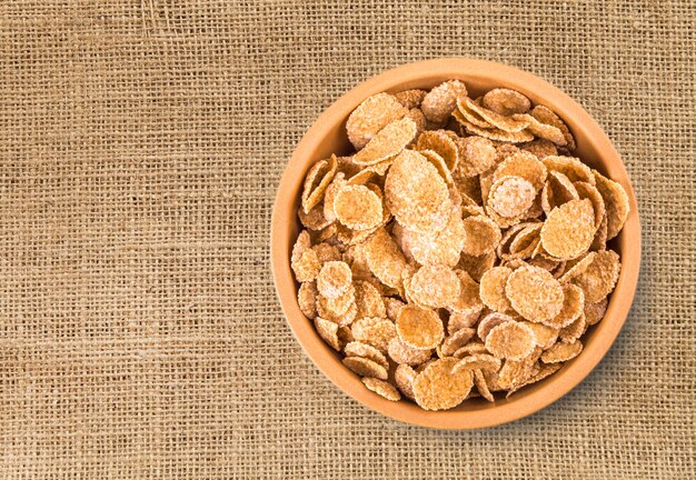 Flakes in a bowl on burlap wall, food closeup