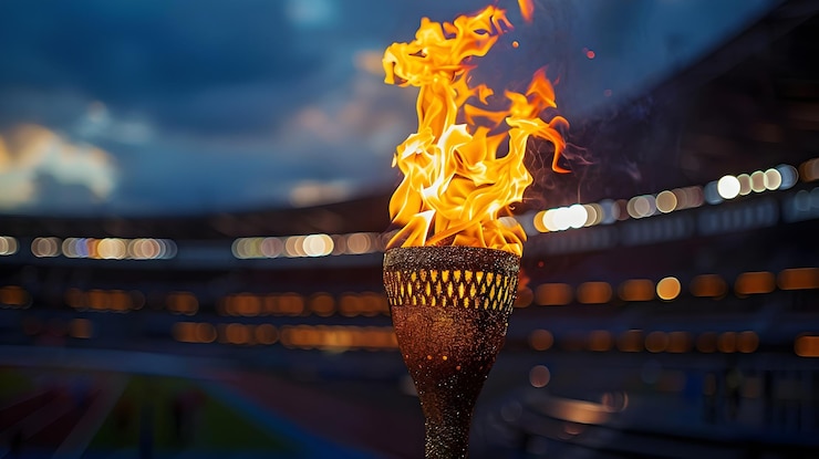 Photo flame burns in olympic torch against blurred sports arena