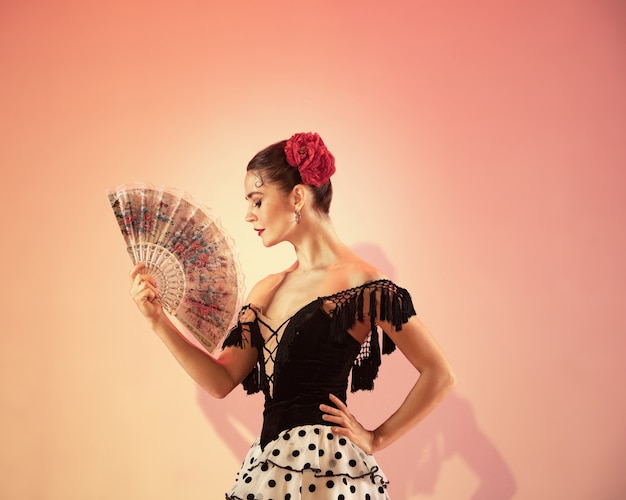 Flamenco dancer Spain woman gypsy with red rose and spanish hand fan posing and dancing at studio