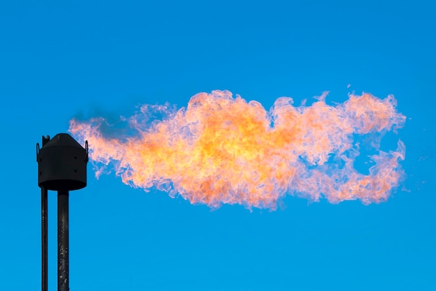 Flames and black pipe against the blue sky