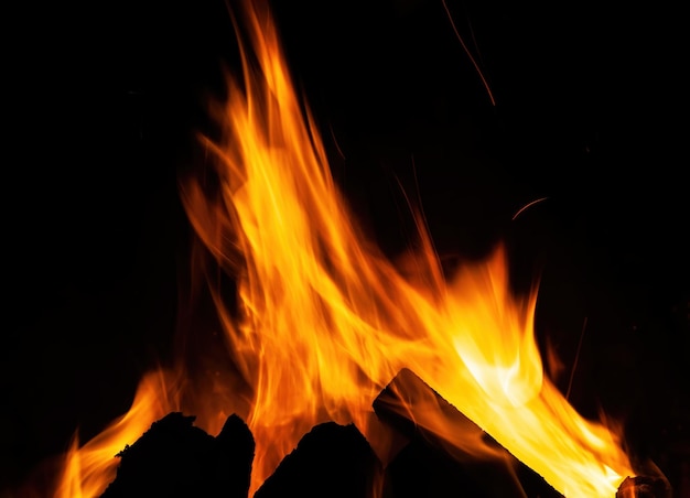 Flames, fire background and texture. Fireplace with wood and fire on a dark background